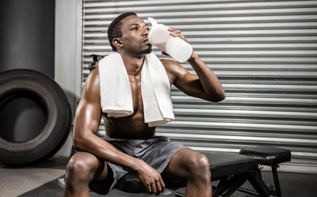 Shirtless man drinking pre-workout shake