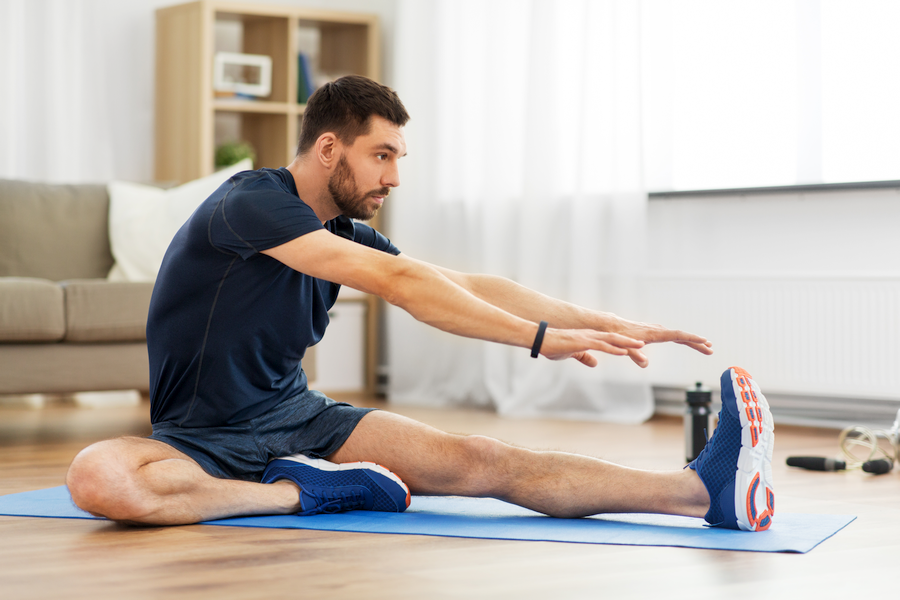 Man performing static leg stretches on the floor.
