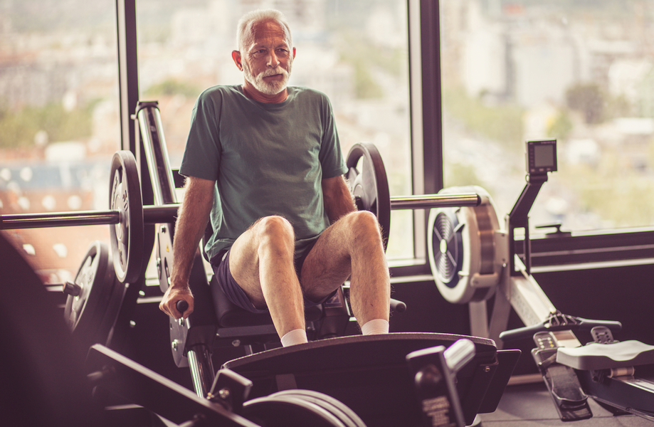 Older man over 50 performing strength training exercises at the gym