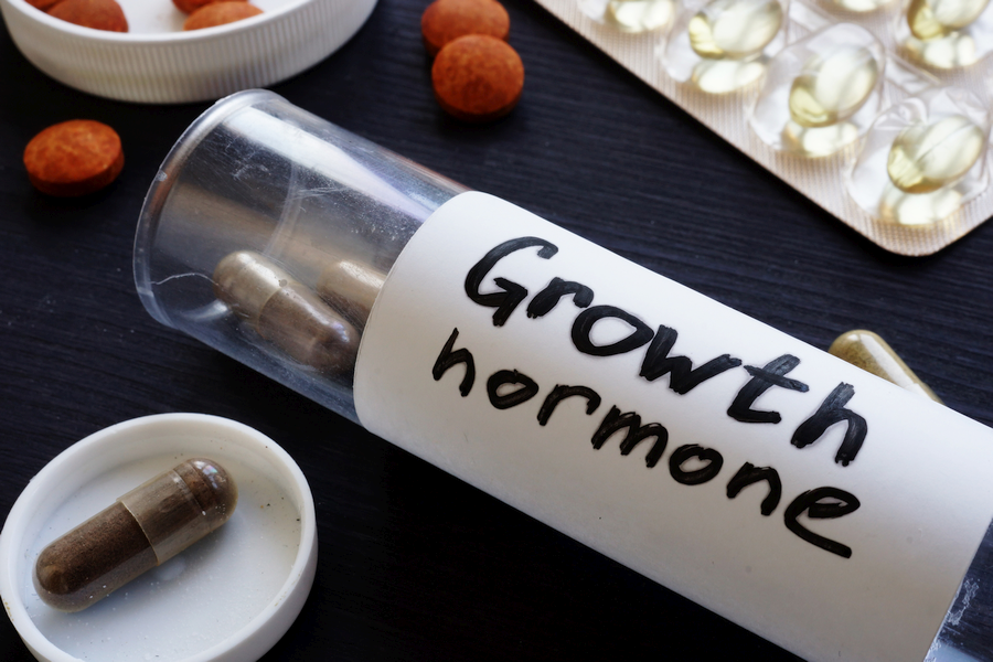 A glass container filled with growth hormone booster capsules, labeled "Growth Hormone"